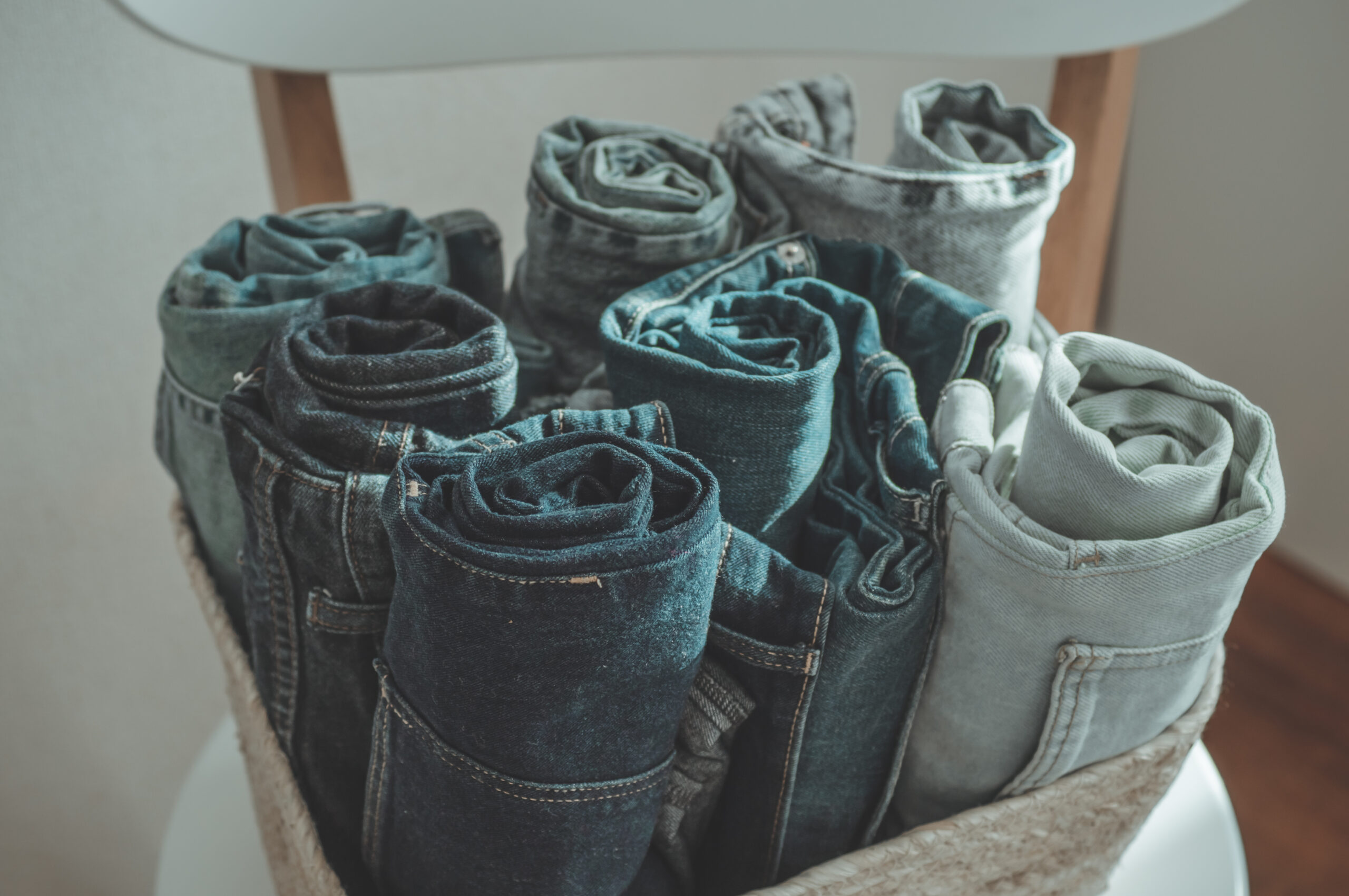 Jeans background. Jeans denim cloth garment monochrome gray blue linen textile stacked on wooden chair near white wall pile concept
